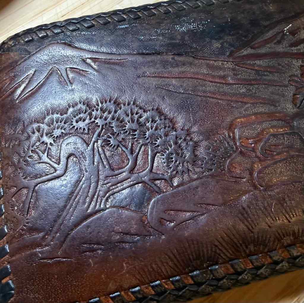 Close-up of a textured leather surface featuring an embossed scenic design of trees and mountains.